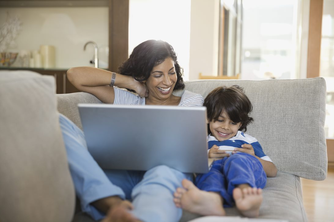 Femme et enfant regardant un ordinateur portatif au sol