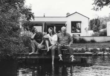 A young man, lady and an elderly gentleman sitting by a dock